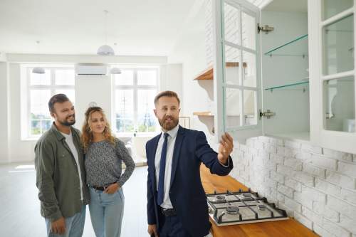 First-time buyers touring a bright kitchen with a real estate agent